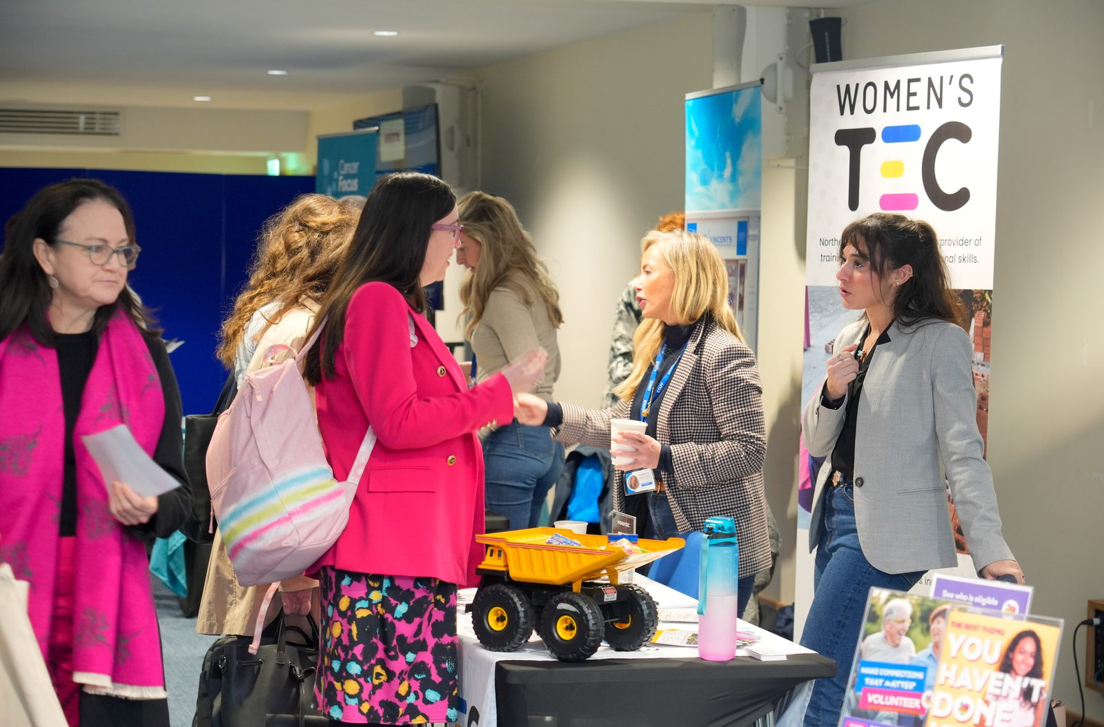 Visitors browsing the Women's TEC stand and other exhibitor displays at the charity job fair