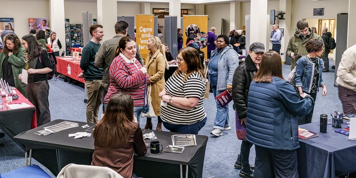 Wide view of the fair venue with dozens of visitors moving between charity exhibition stands