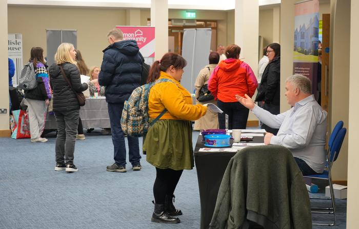 A busy aisle of visitors queuing and browsing at charity stands