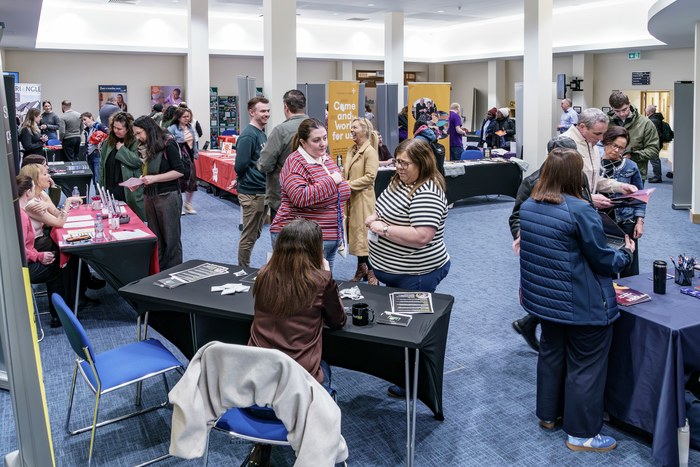 A wide view of the fair hall filled with stands and visitors
