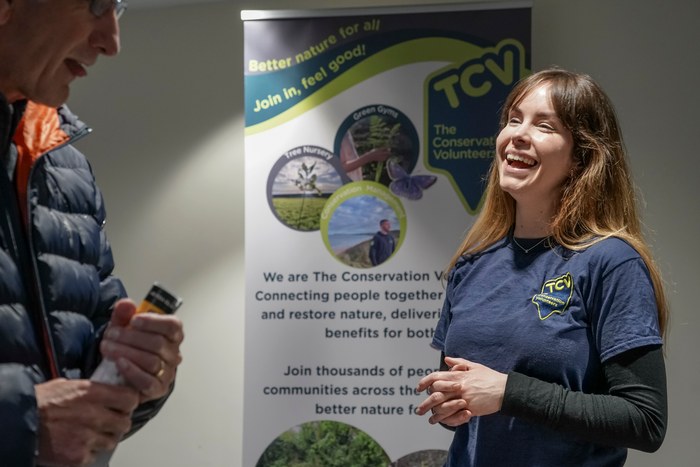 A smiling exhibitor beside The Conservation Volunteers banner