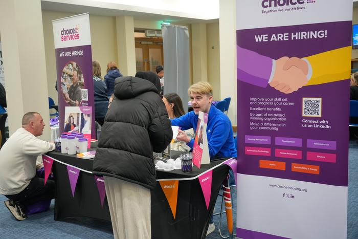 A busy hiring stand with bunting and branded banners surrounded by visitors