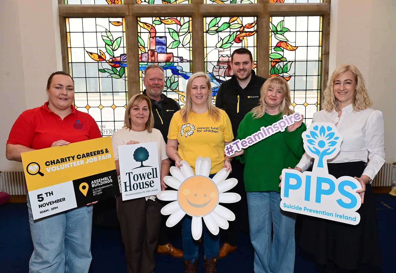 Representatives from health and wellbeing charities, including Towell House and PIPS, holding branded signs at Assembly Buildings, Belfast