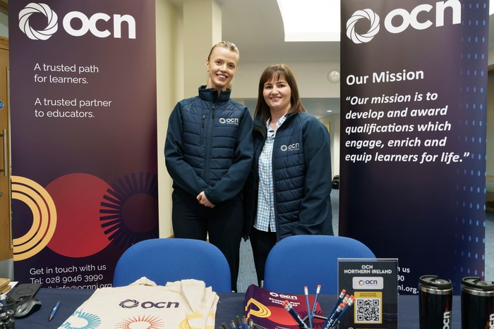 Two exhibitors standing in front of the OCN Northern Ireland stand