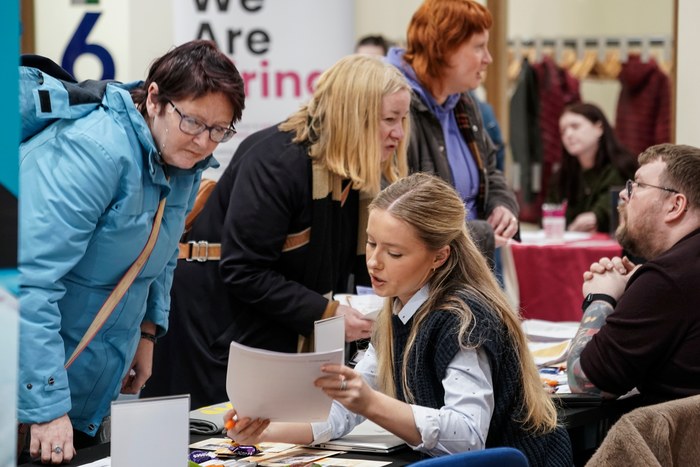 Visitors handing over paperwork at a busy charity recruitment stand