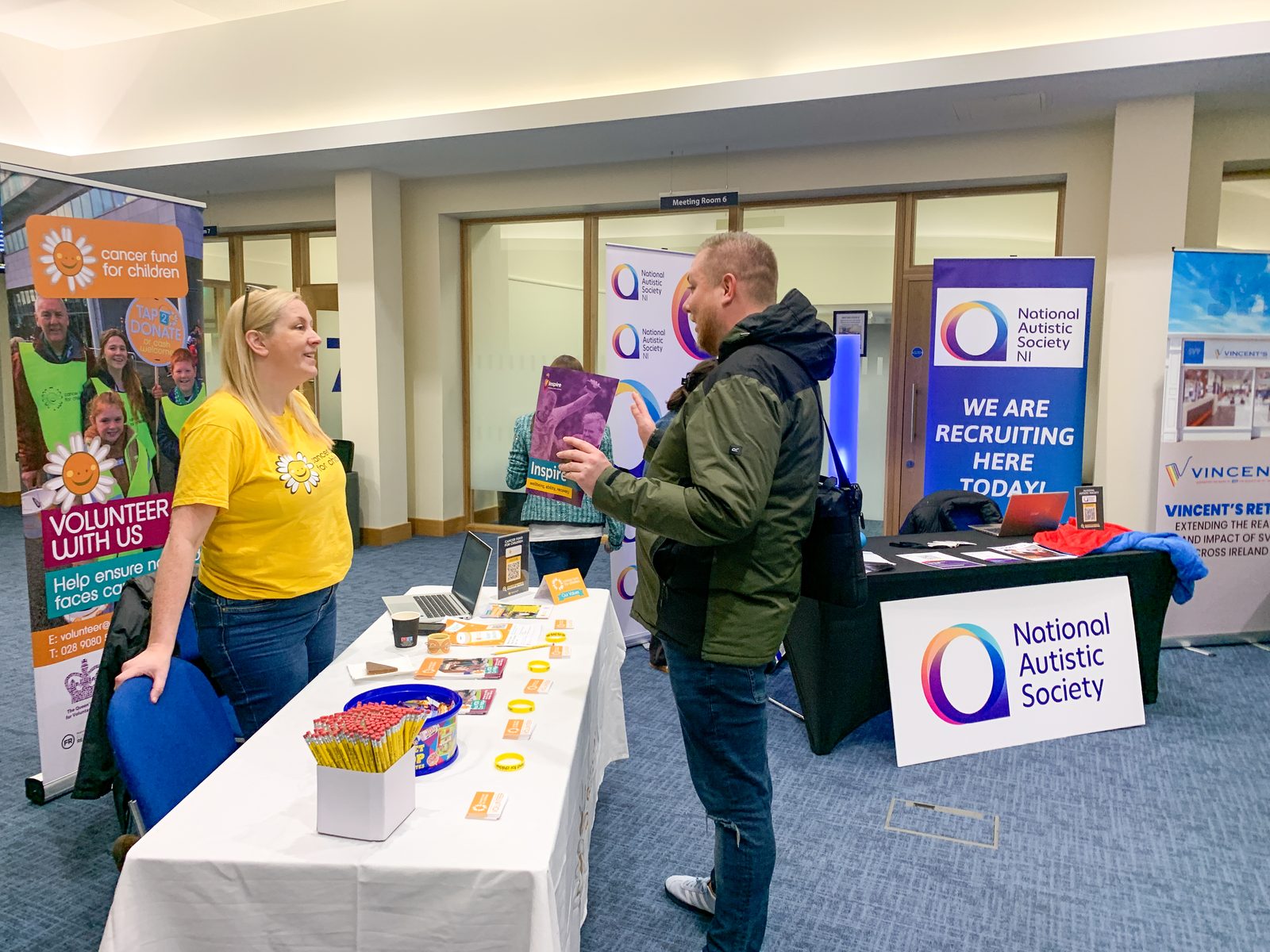 A visitor talking to a National Autistic Society volunteer at an exhibition stand during the job fair