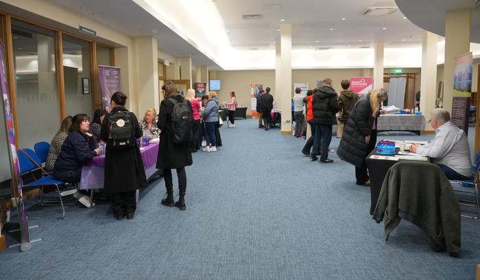 A long row of charity exhibition stands with visitors browsing information