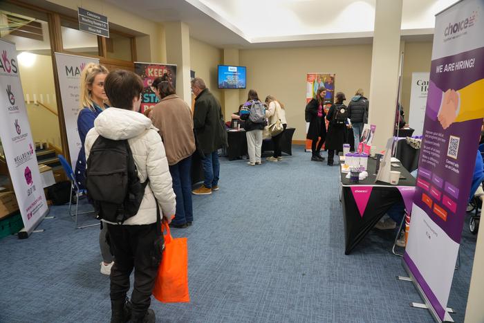 A large crowd of visitors moving between charity stands at the fair