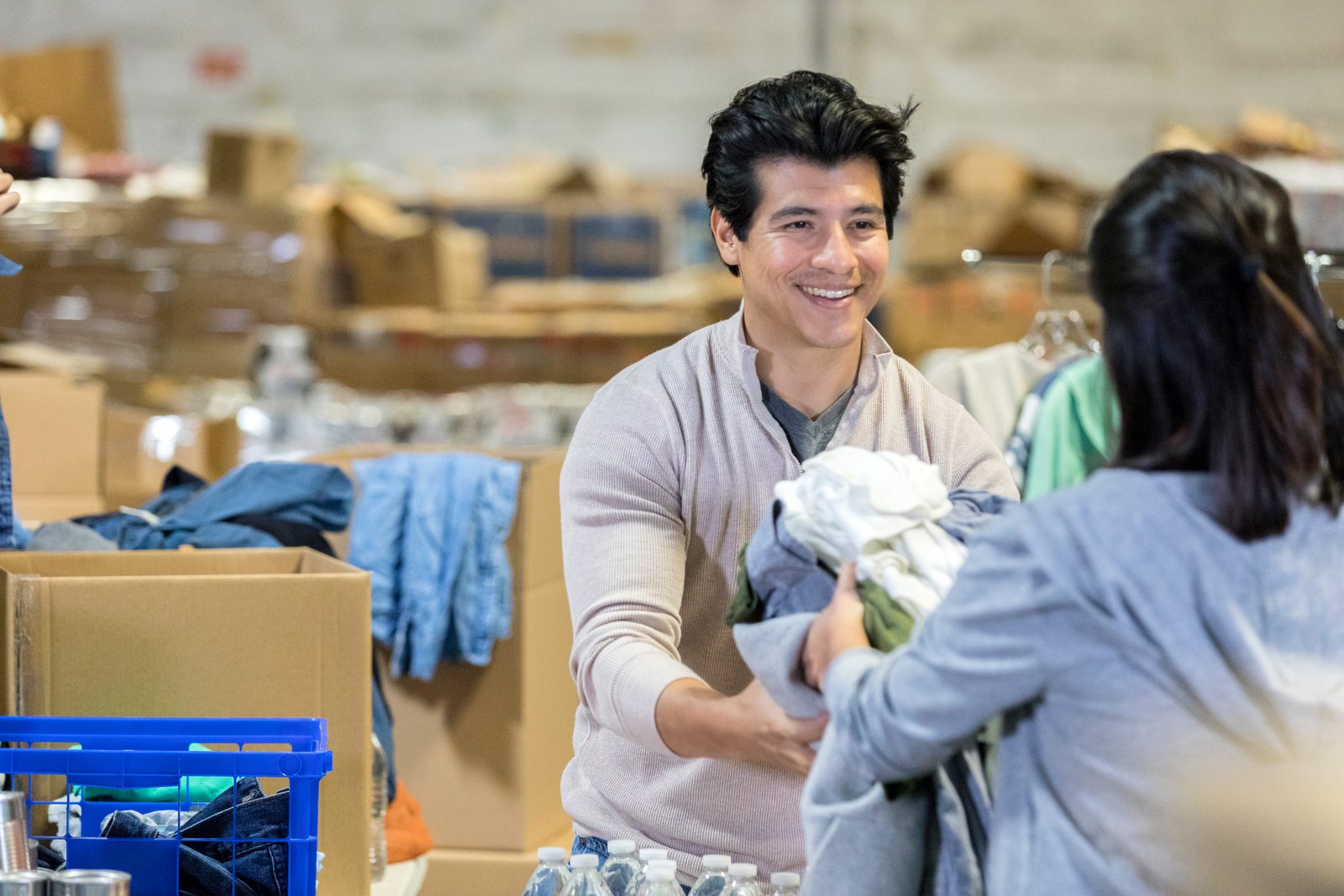 Two charity volunteers sorting donated clothing into boxes at a community collection point