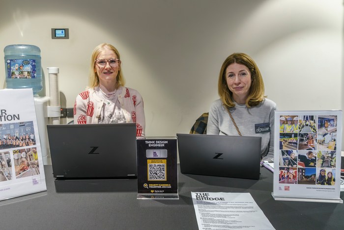 Two exhibitors at a stand with laptops showing current vacancies