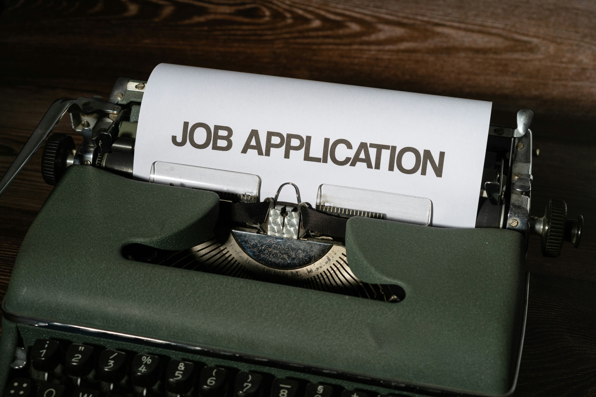 Typewriter holding a sheet of paper headed "Job Application"